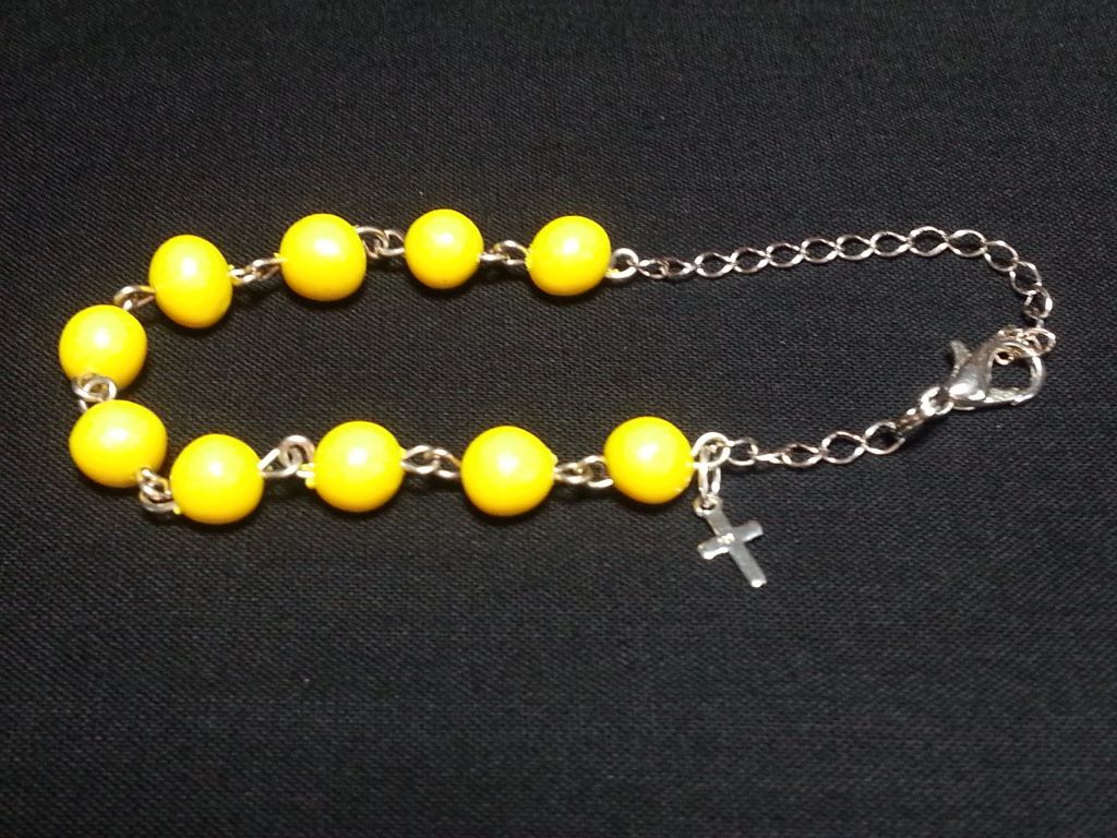 a bracelet with yellow beads and a cross on it