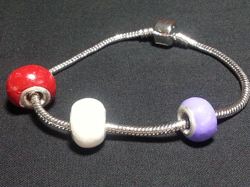 a silver bracelet with red white and purple beads