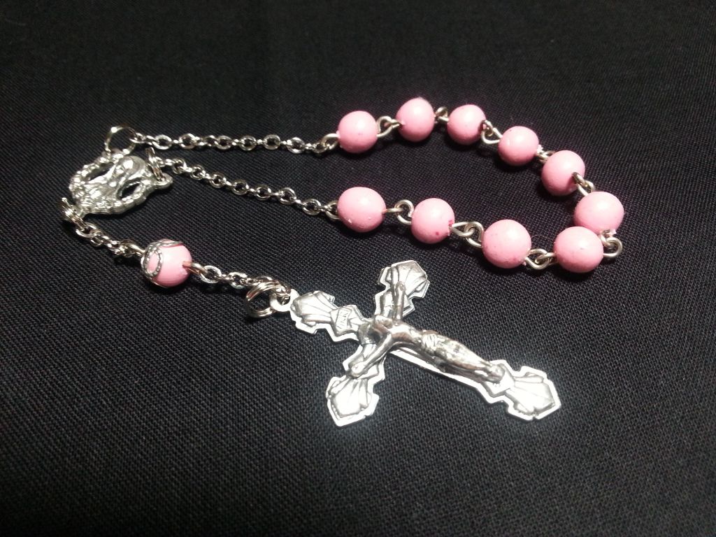 a rosary with pink beads and a silver cross