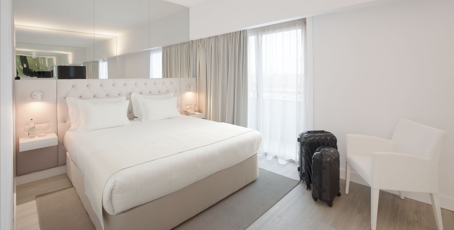 Um quarto de hotel com uma cama king size, cadeira e bagagem.
