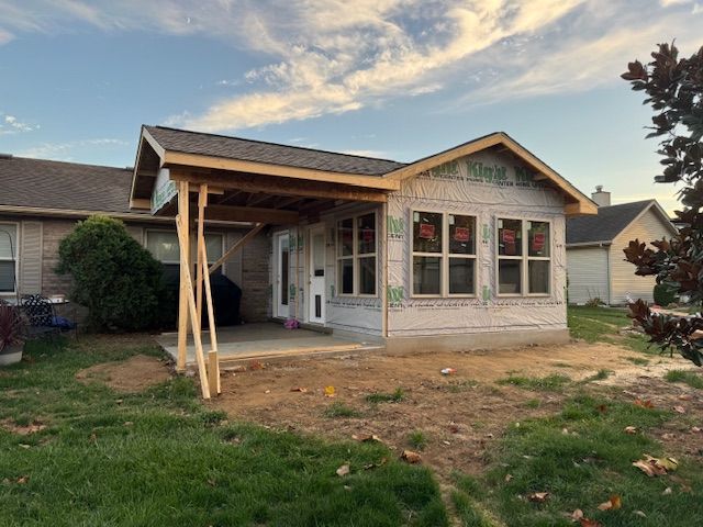 A small house is being built with a porch and a roof.