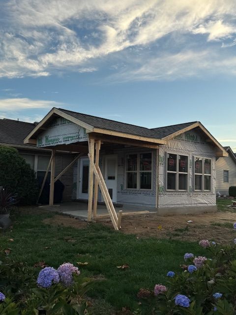 A house under construction with a porch and flowers in front of it