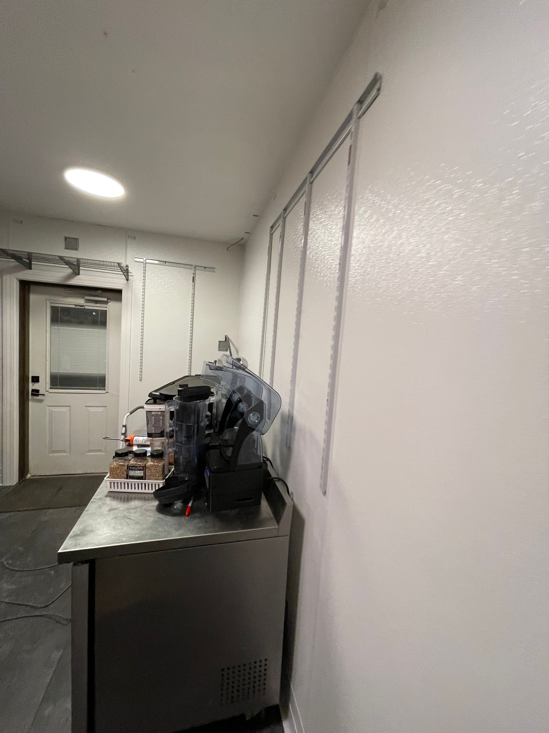 A kitchen with a stainless steel counter and a white wall.