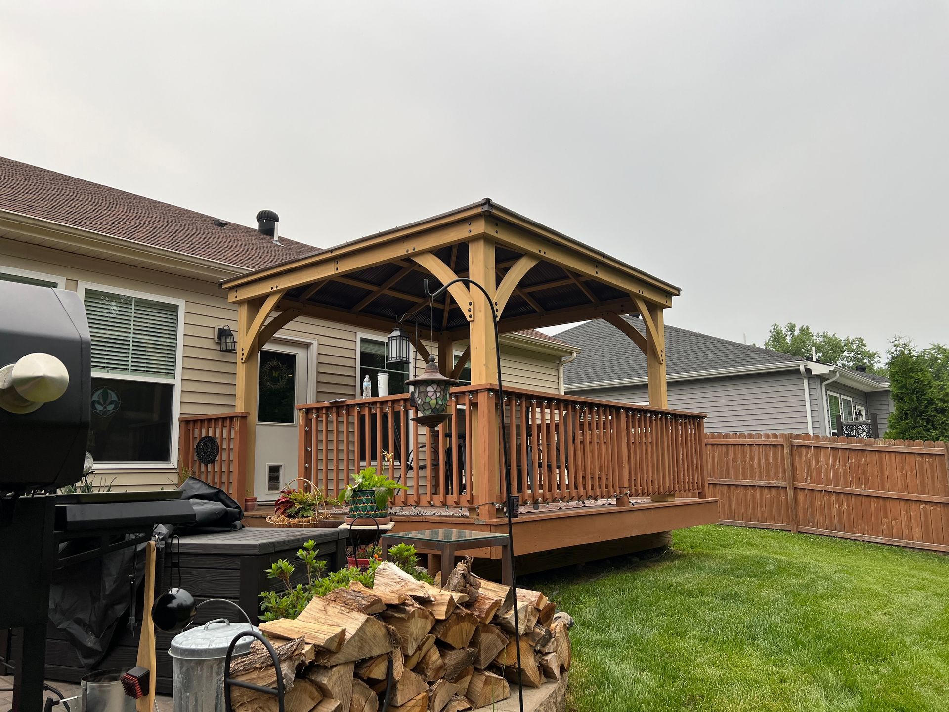 A wooden deck with a gazebo in the backyard of a house.
