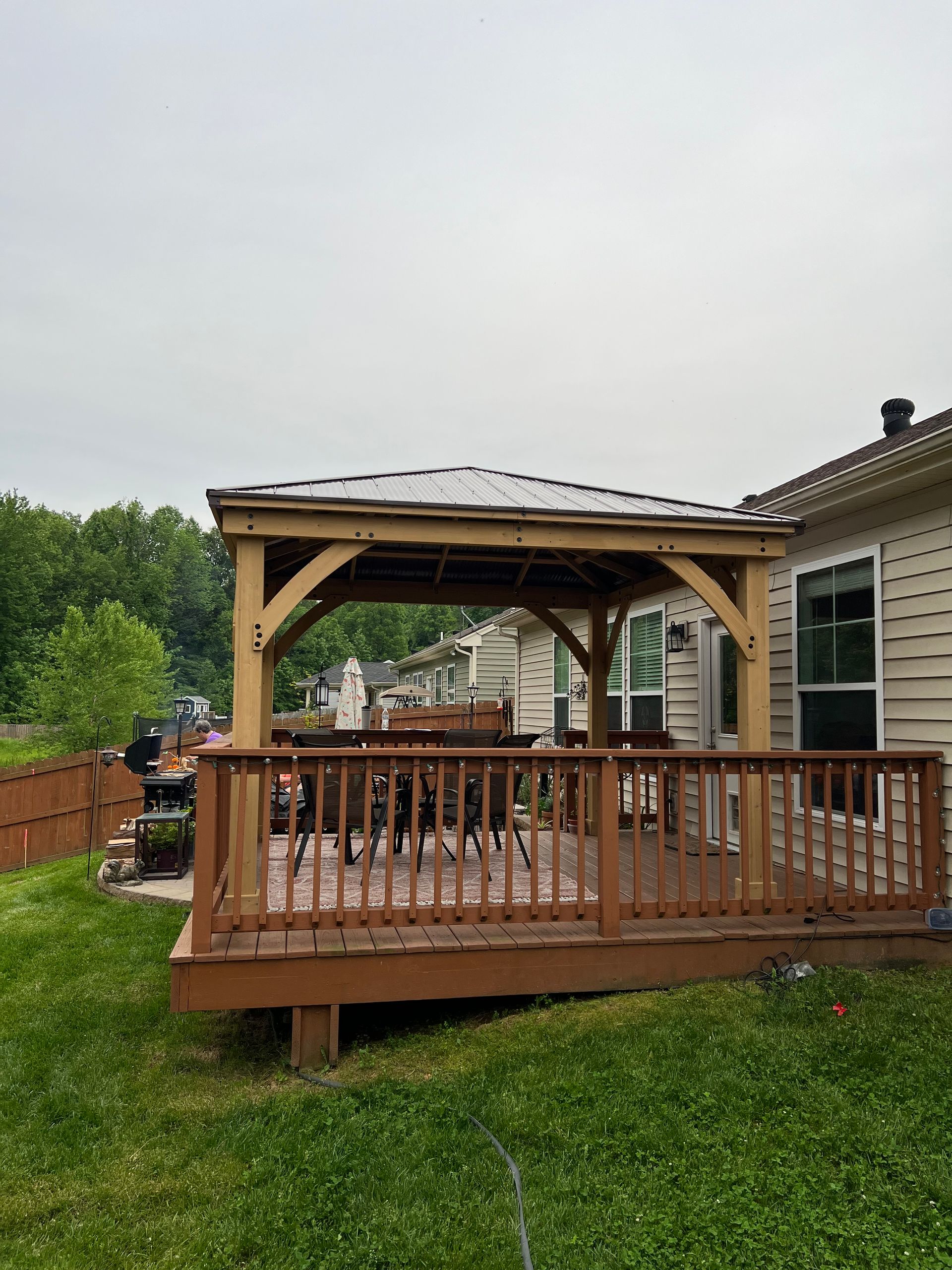 A wooden deck with a gazebo in the backyard of a house.