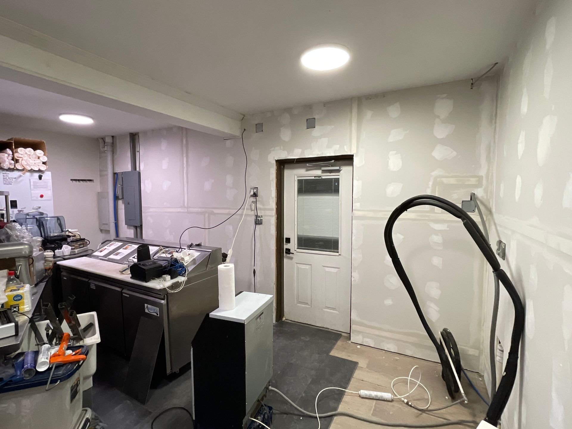 A room with a lot of wires hanging from the ceiling and a door.