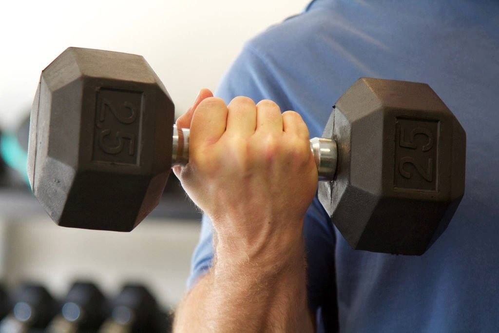 A man is lifting a dumbbell in a gym.