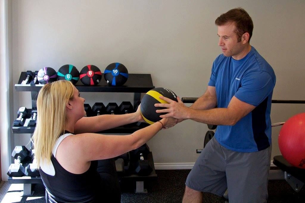A man and a woman are holding a medicine ball in a gym
