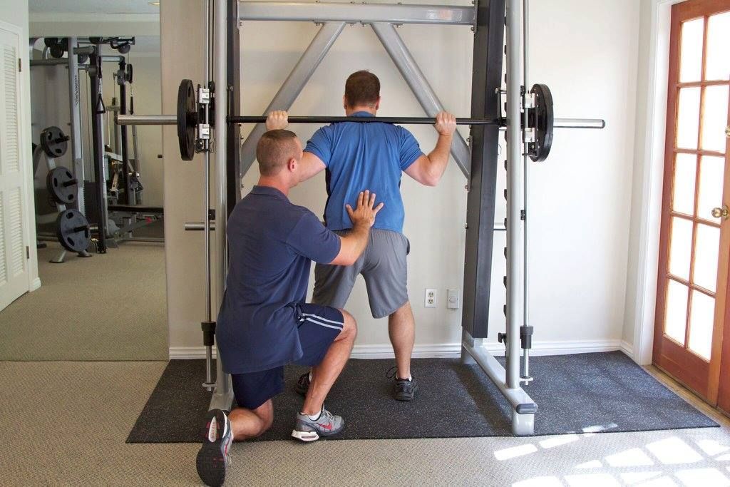 A man squatting with a barbell in a gym