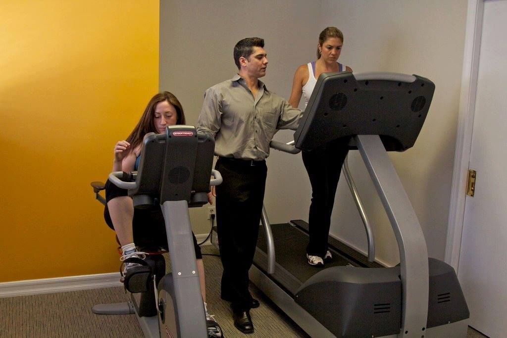 A man is helping a woman on a treadmill in a gym