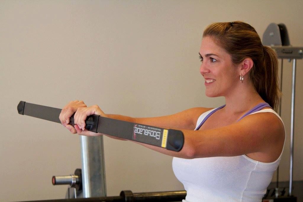A woman is using a machine in a gym and smiling.