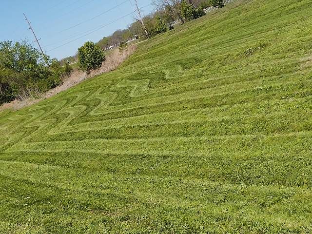 Green hillside with zigzag and striped mowing patterns.
