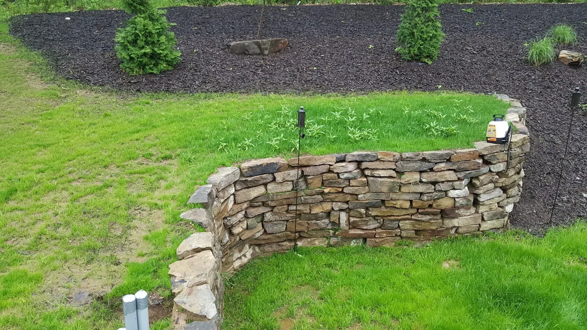 Wooden retaining walls holding bushes and flowers near a pathway.