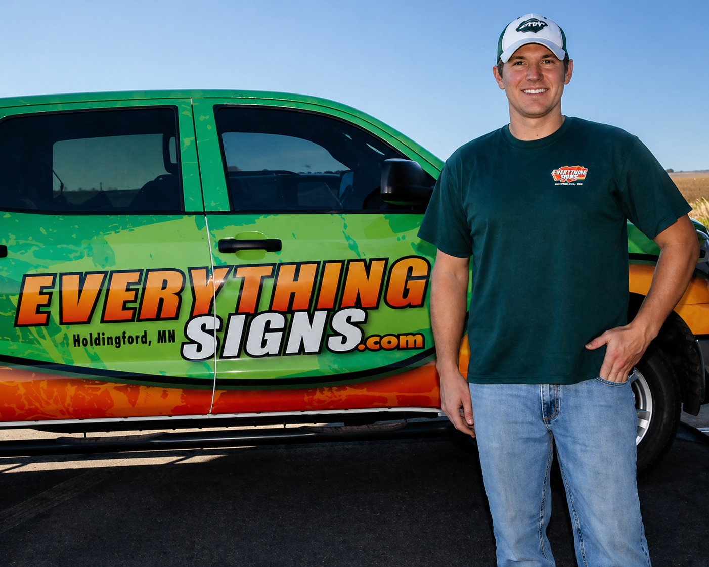 Man standing beside green vehicle wrapped with “Everything Signs.com” advertisement