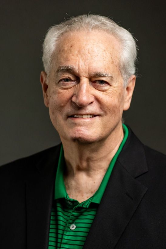 A woman is sitting at a desk with a laptop and a vase of flowers.