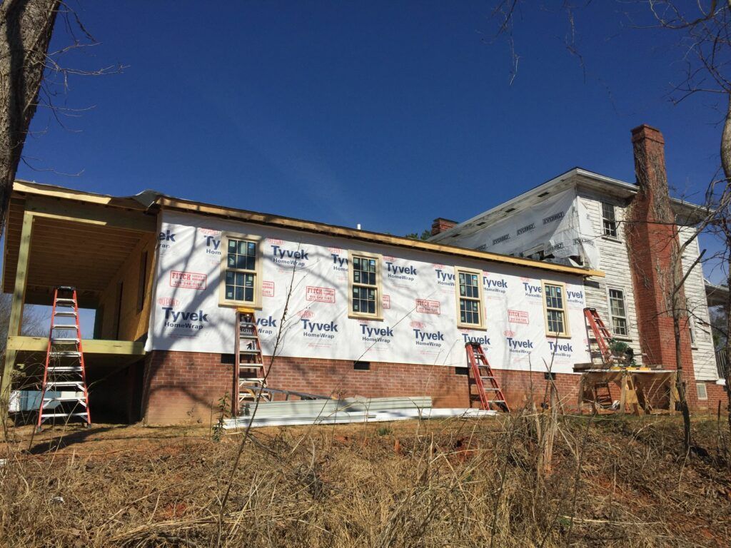 A house is being remodeled with a lot of windows and a chimney.