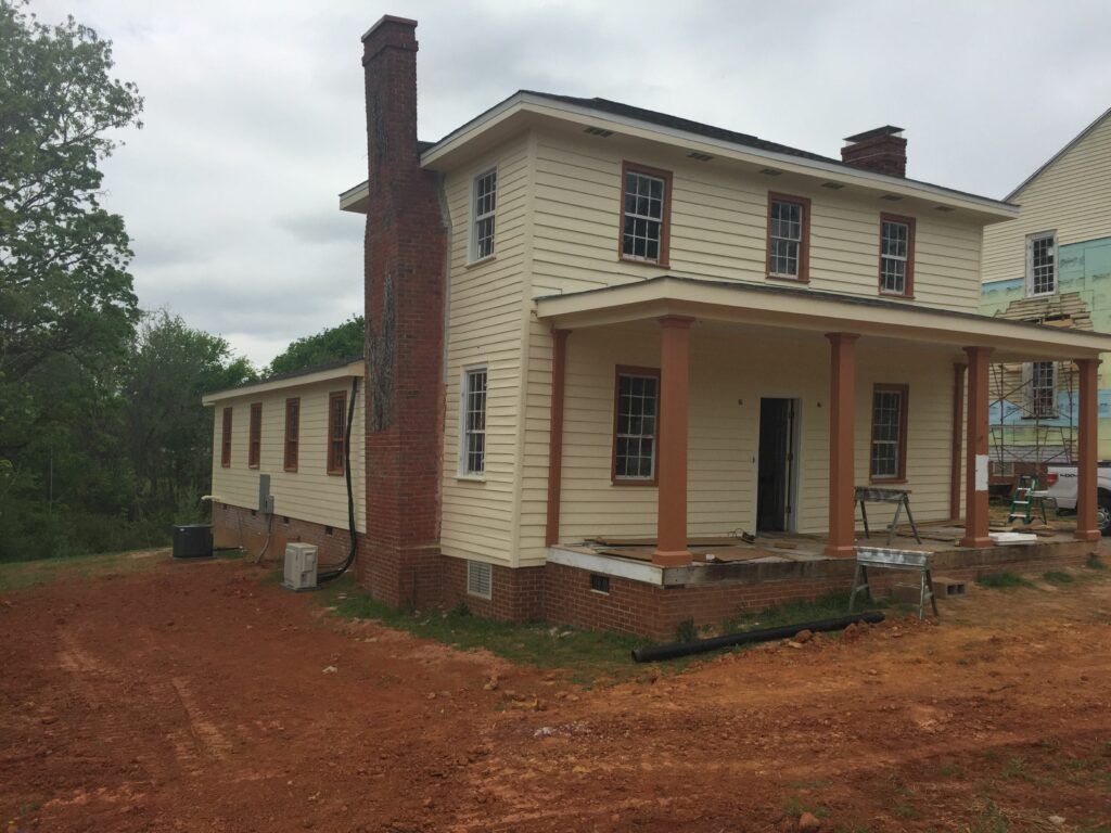 A large white house with a porch and a brick chimney