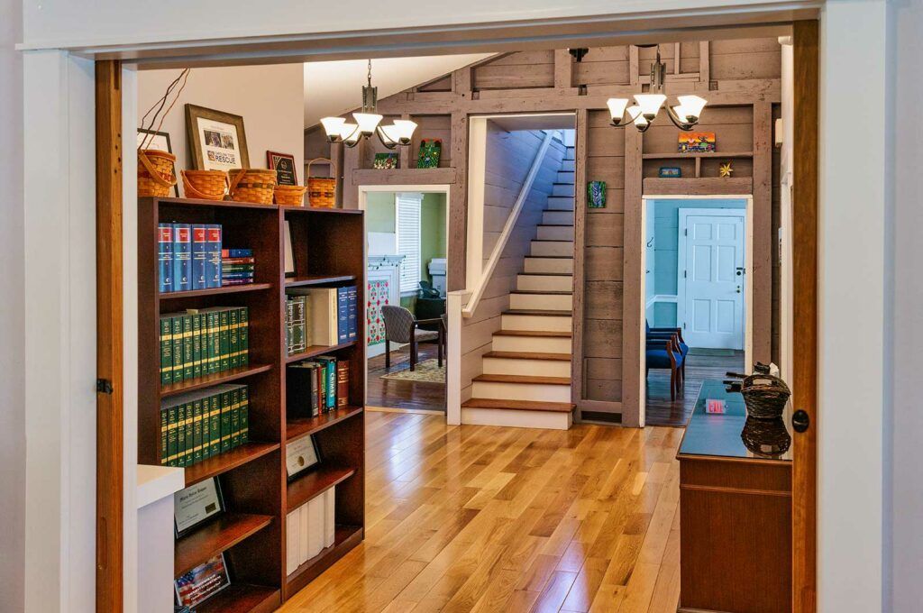 A hallway with hardwood floors and bookshelves and stairs
