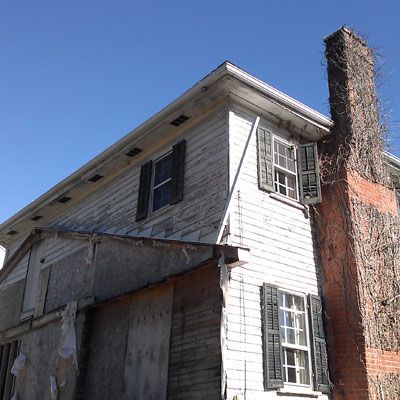A white house with black shutters and a brick chimney