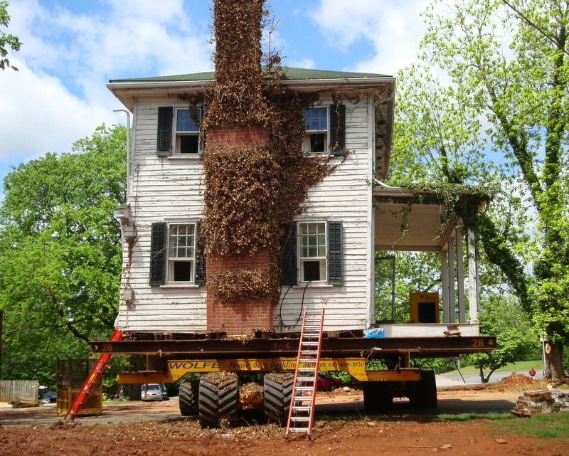 A house is being moved by a tractor with a ladder attached to it