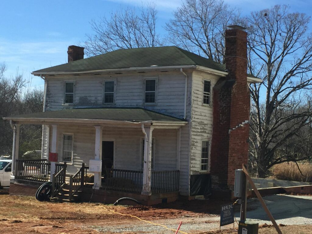 A white house with a green roof and a brick chimney