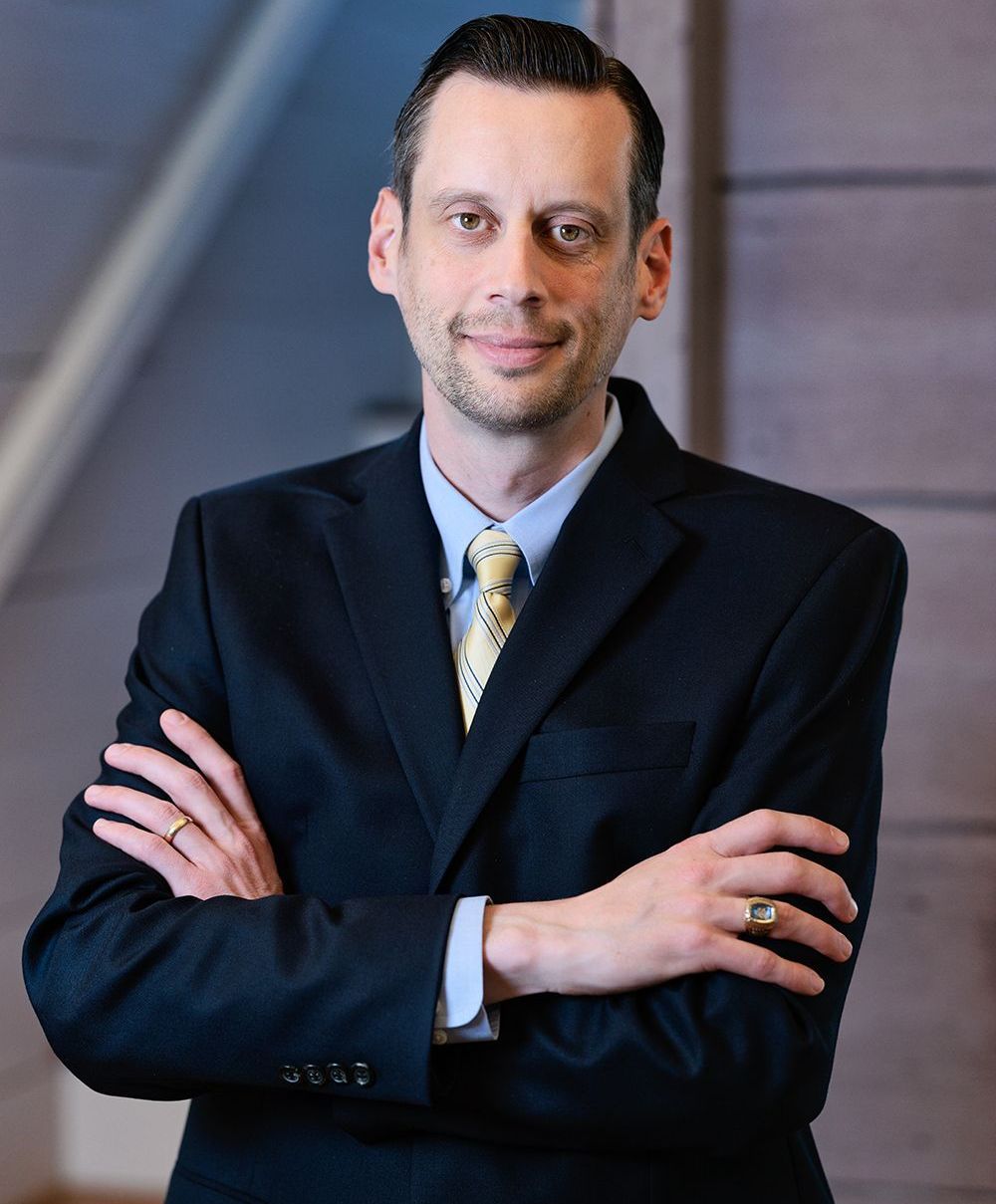 A man in a suit and tie with his arms crossed