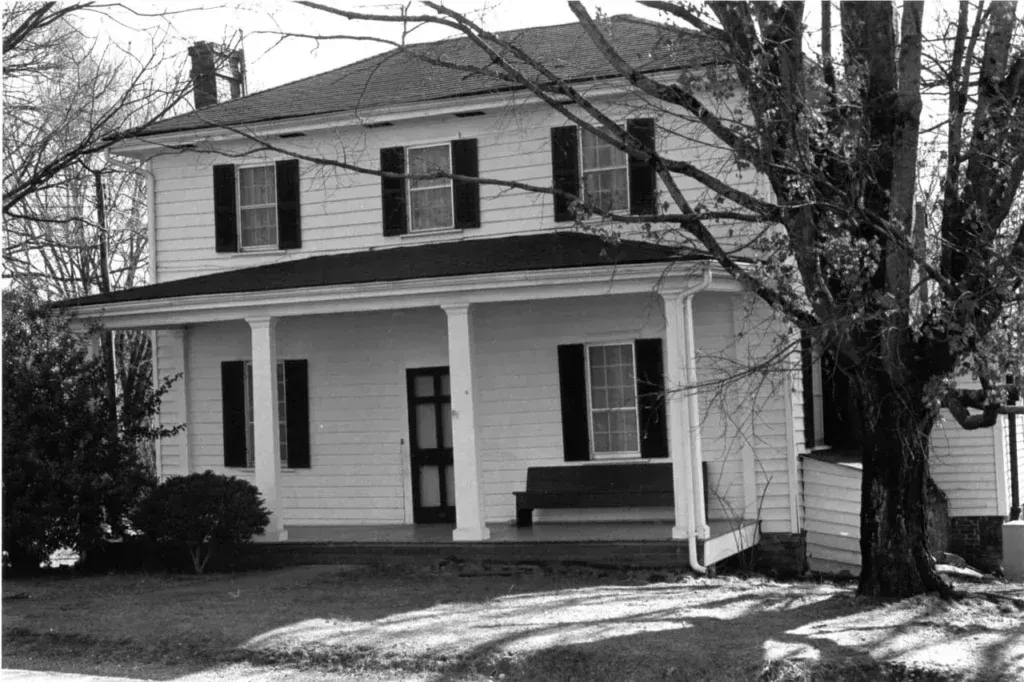 A black and white photo of a house with a porch