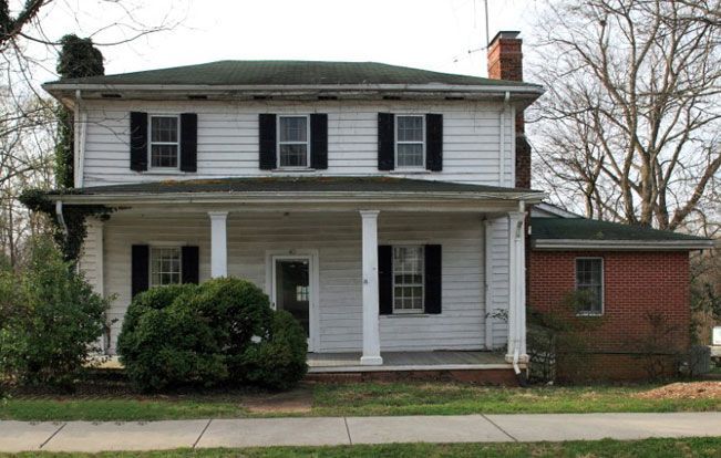 A white house with black shutters and a green roof