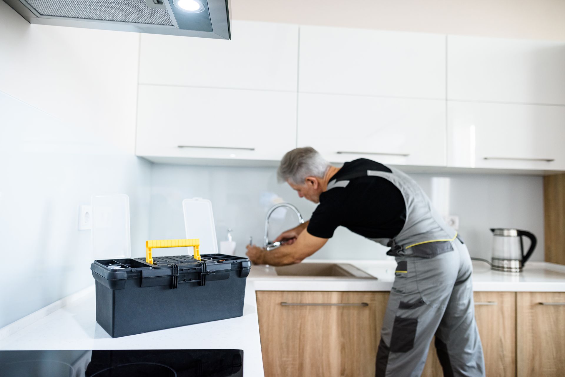 A man is fixing a faucet in a kitchen.