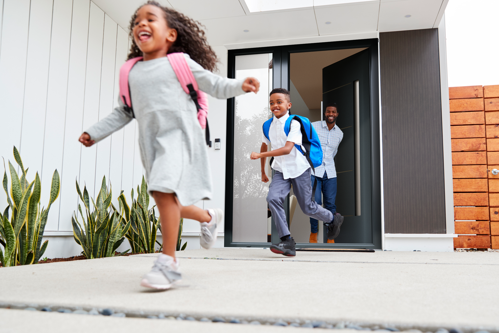 A group of children are running out of a house.