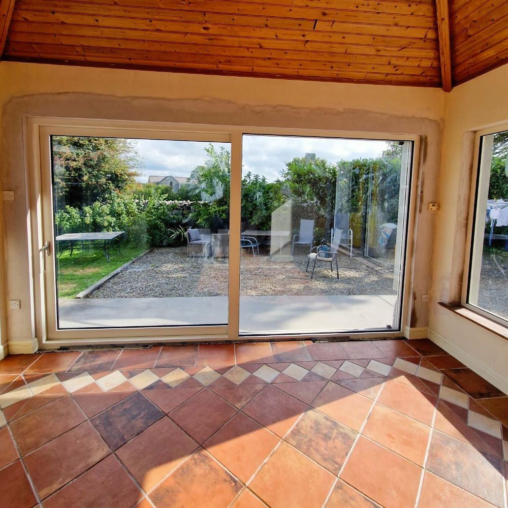 An empty room with a sliding glass door and a tiled floor