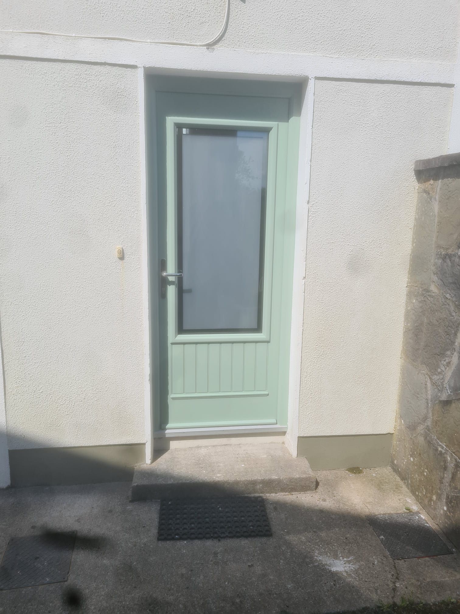 A green door with a glass window is on the side of a building.