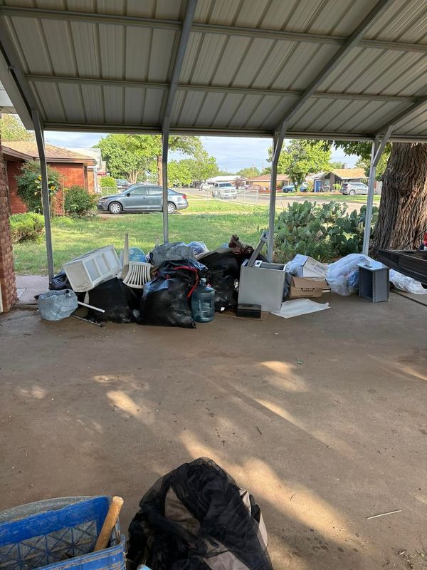 A pile of trash is sitting under a covered porch.