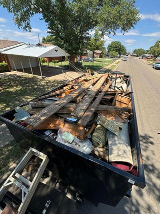 A dumpster filled with junk is parked on the side of the road.