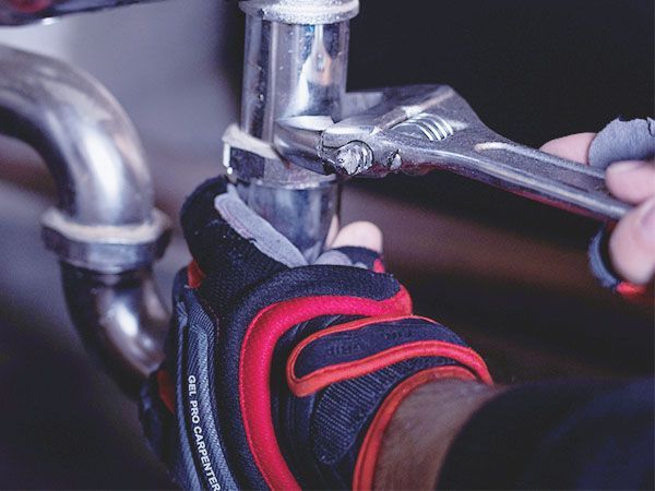 A person is fixing a pipe with a wrench.