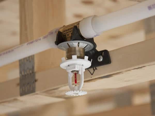 A fire sprinkler is hanging from the ceiling of a building under construction.