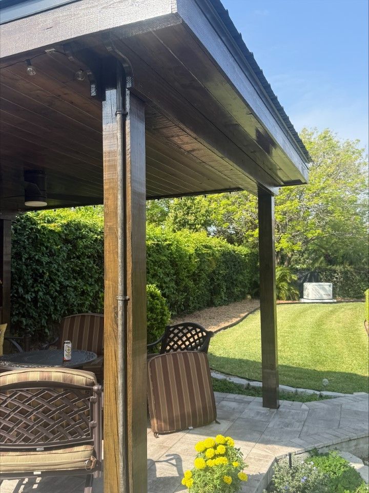 A patio with a wooden roof and a lawn in the background.