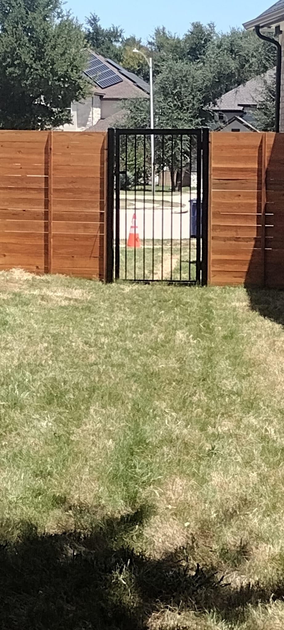 A wooden fence with a gate in the middle of a lush green field.