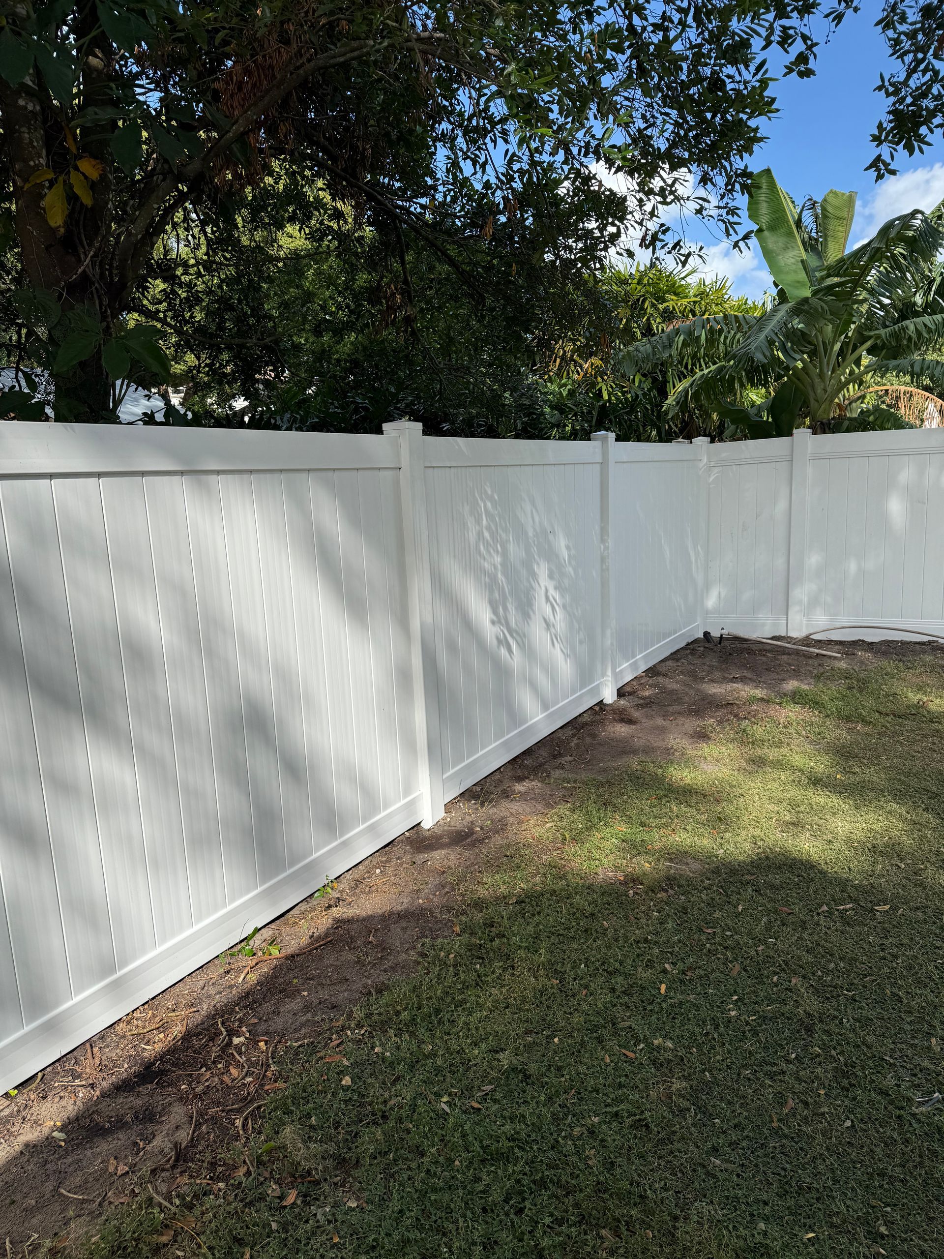 A white fence is in the middle of a lush green yard.