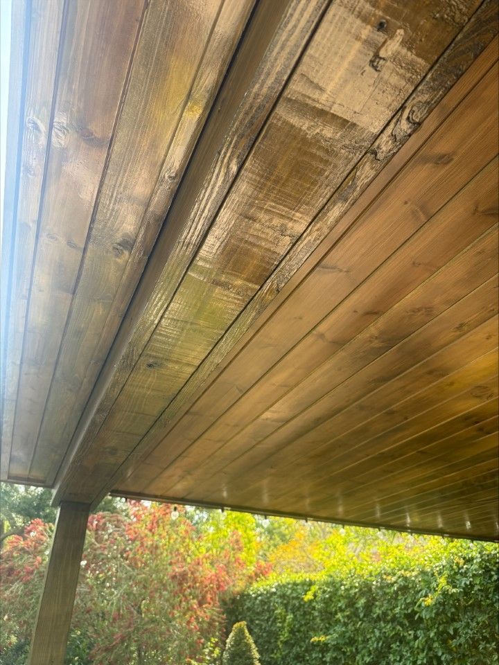 The ceiling of a wooden porch with trees in the background.