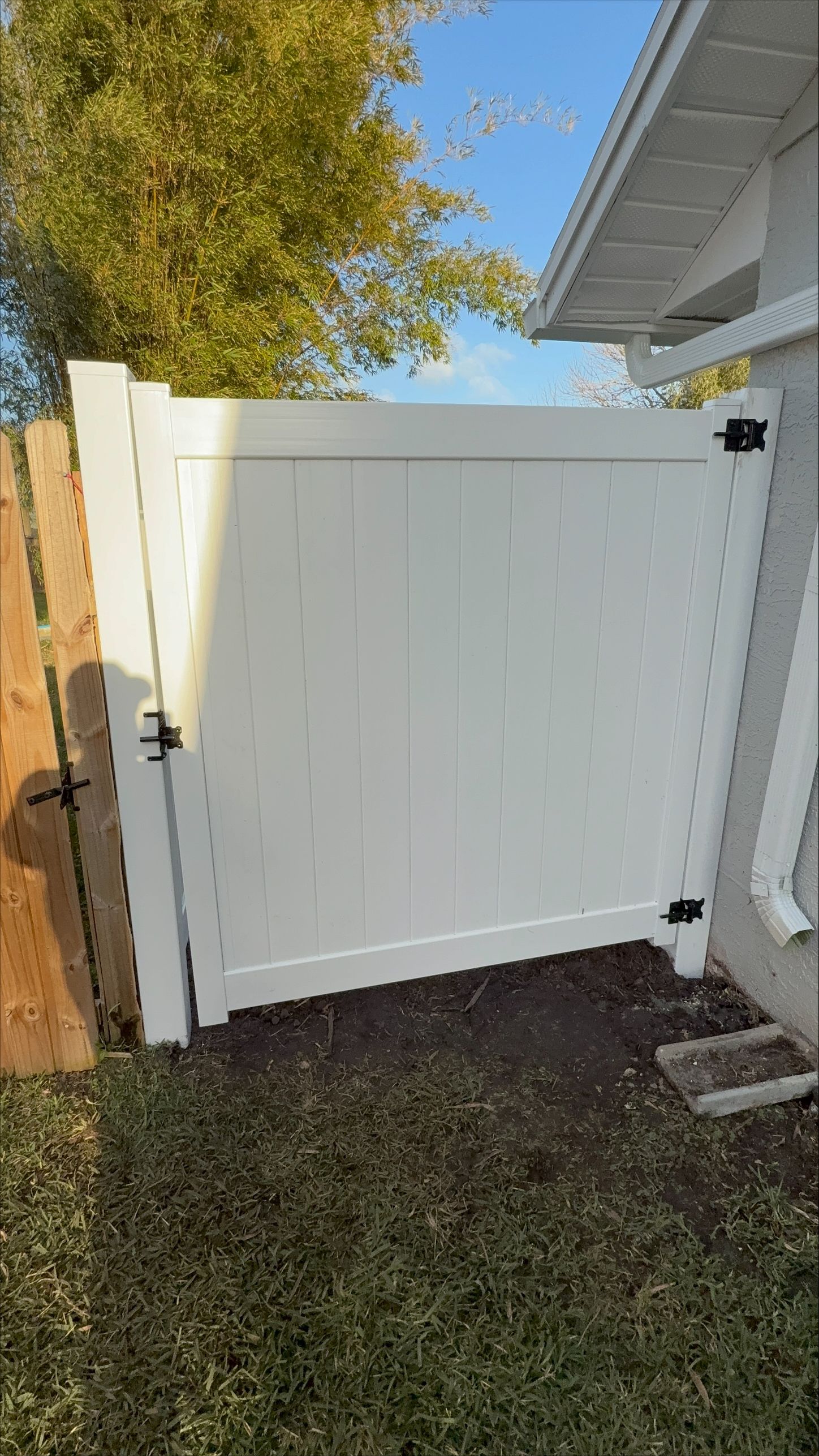 A white vinyl fence surrounds a lush green yard.