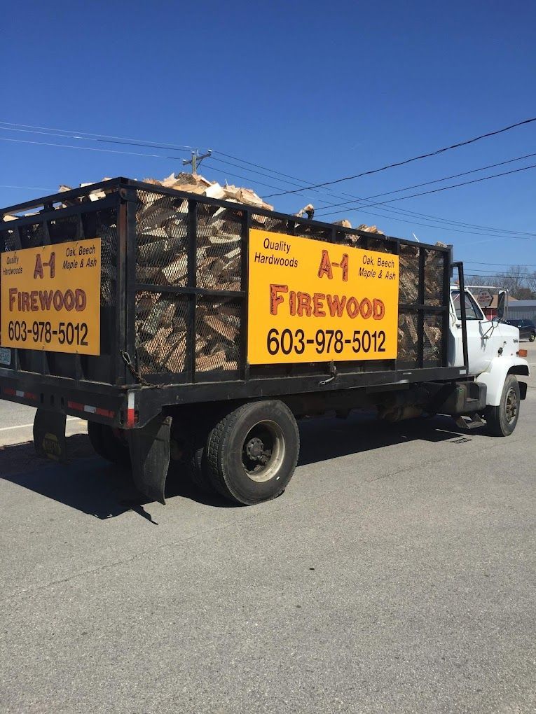 A truck filled with firewood is parked on the side of the road.
