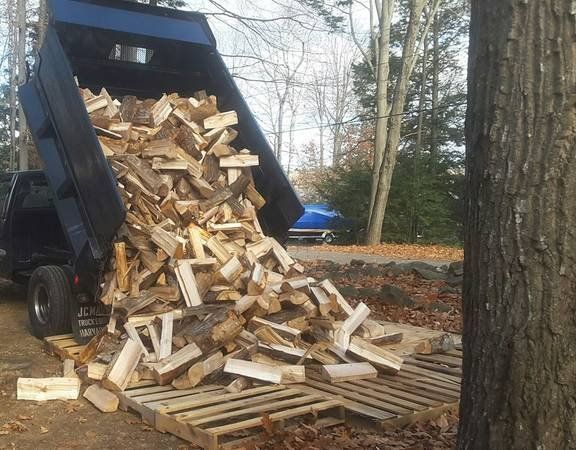 A dump truck is carrying a large pile of wood.
