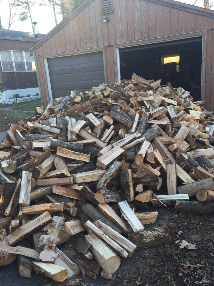 A pile of wood is sitting in front of a garage.