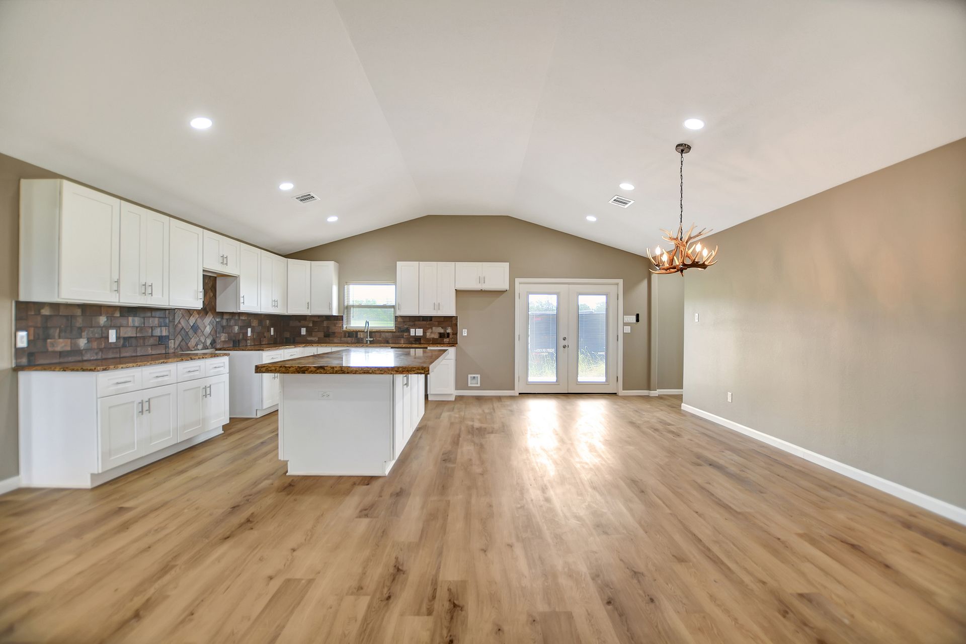 Open-concept kitchen and living space with white cabinets, wood floors, and an island, in a home.