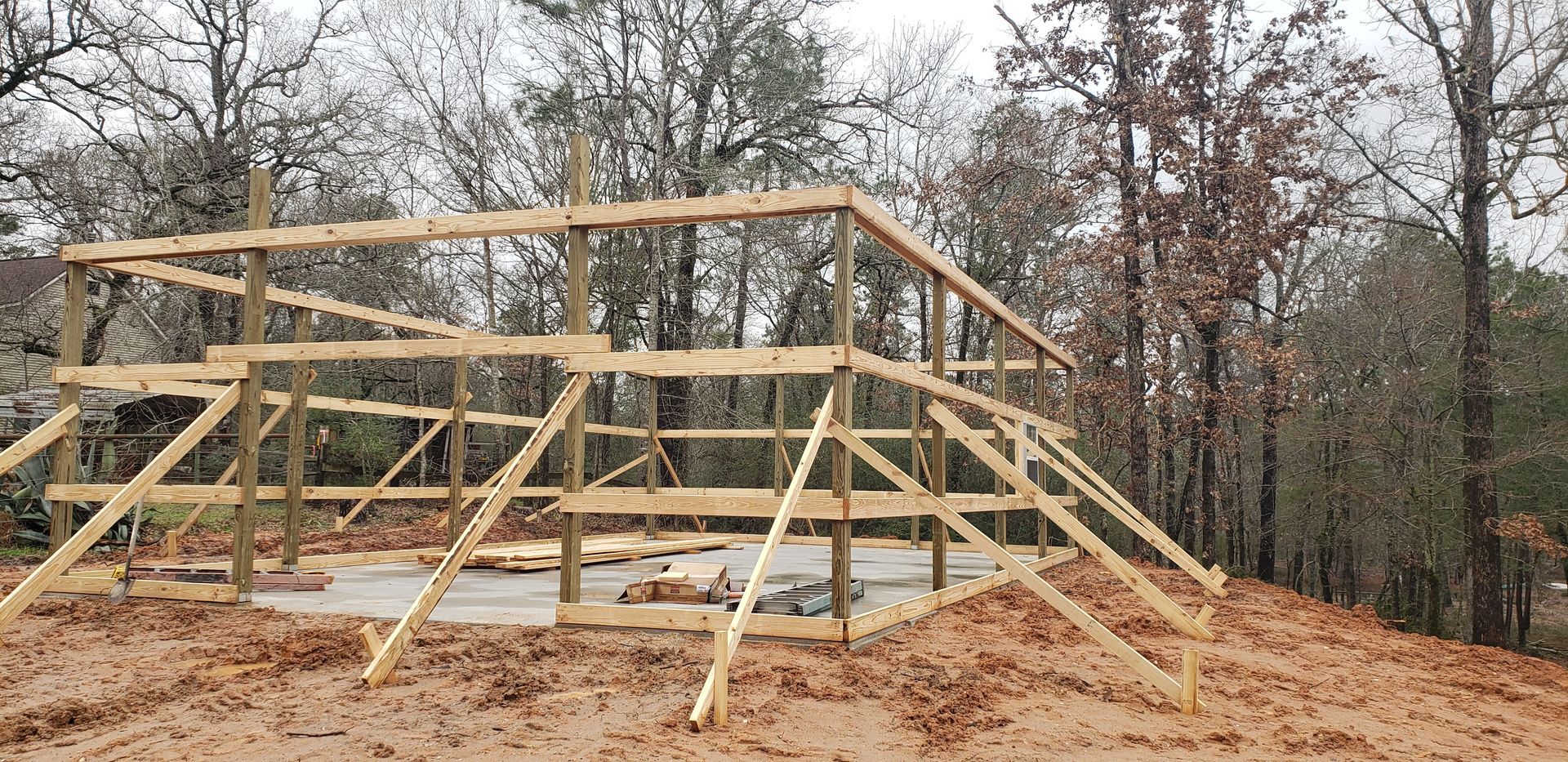 Wooden frame of a building under construction; set in a wooded area.