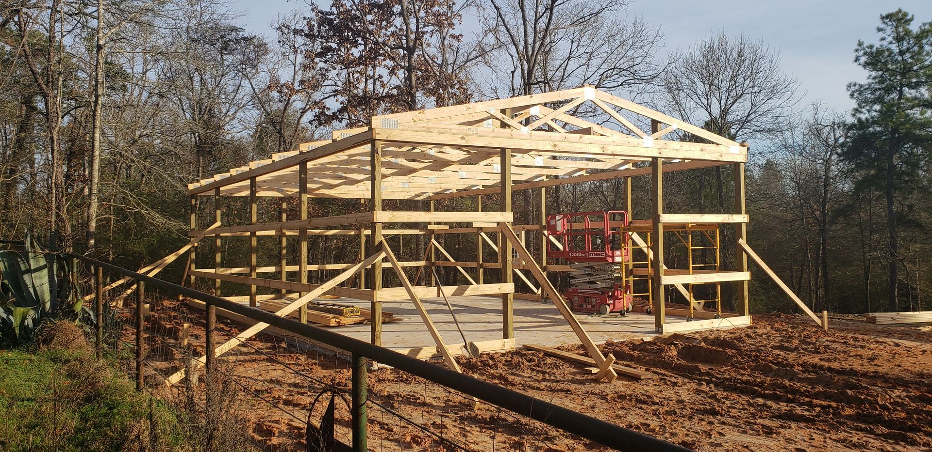Wooden frame of a building under construction in a wooded area.