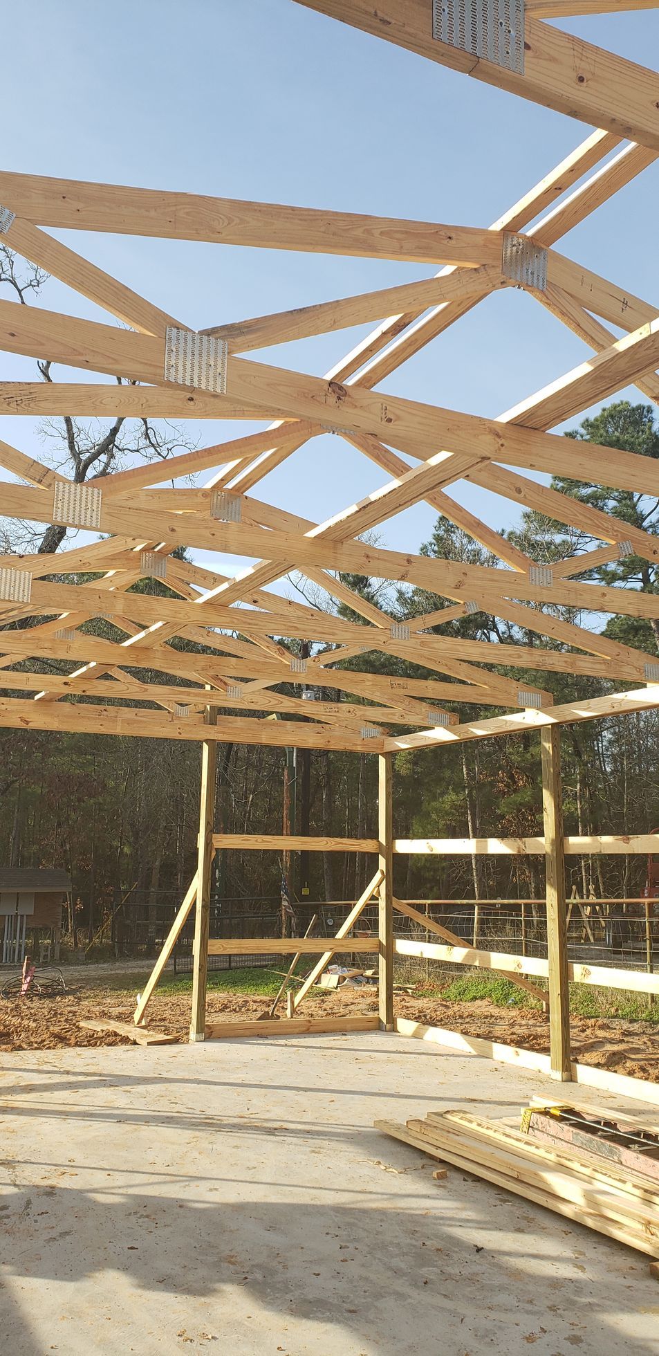Wooden framing of a building under construction against a clear blue sky.