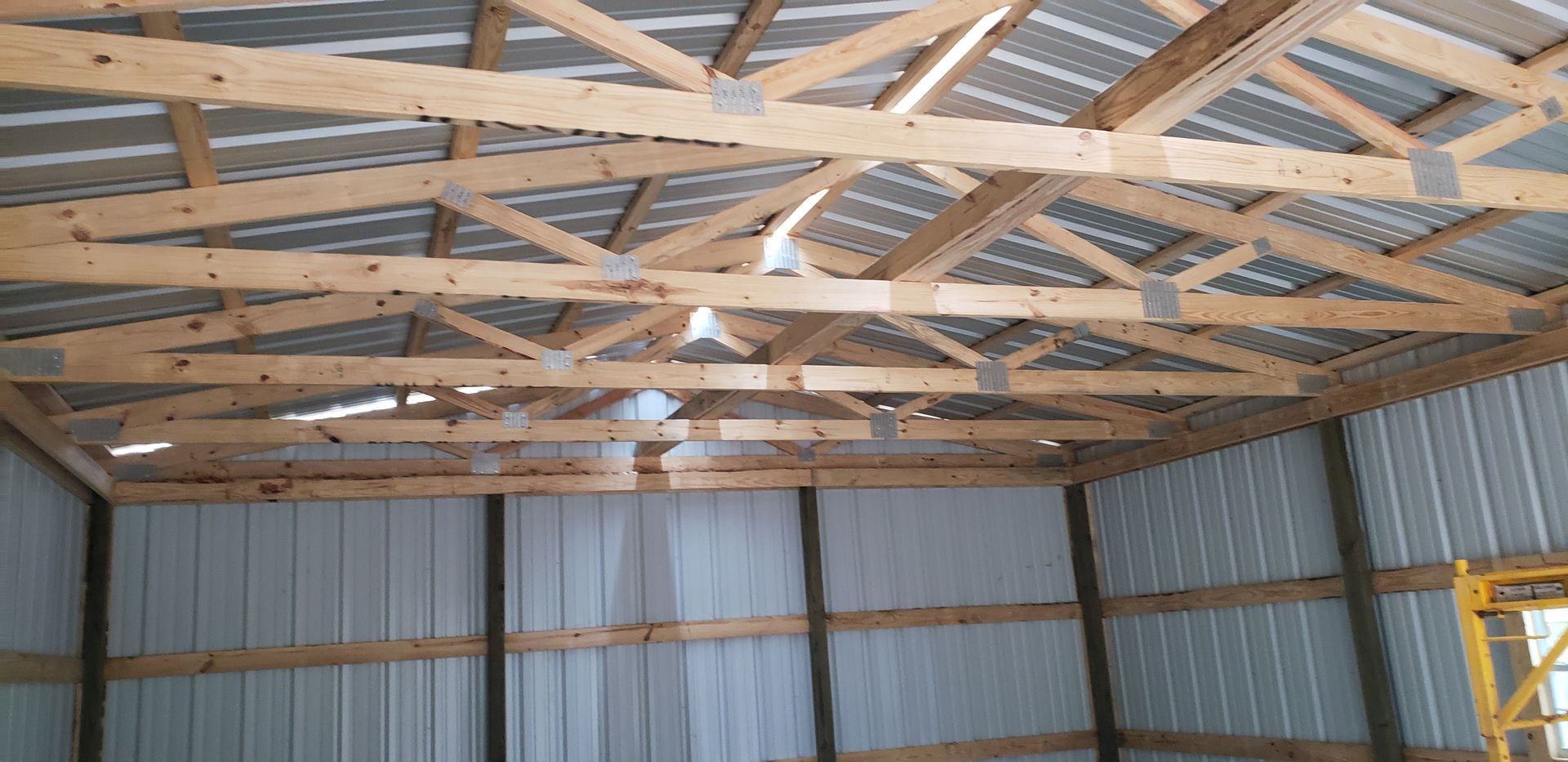 Interior view of a building under construction. Wooden beams and metal siding.