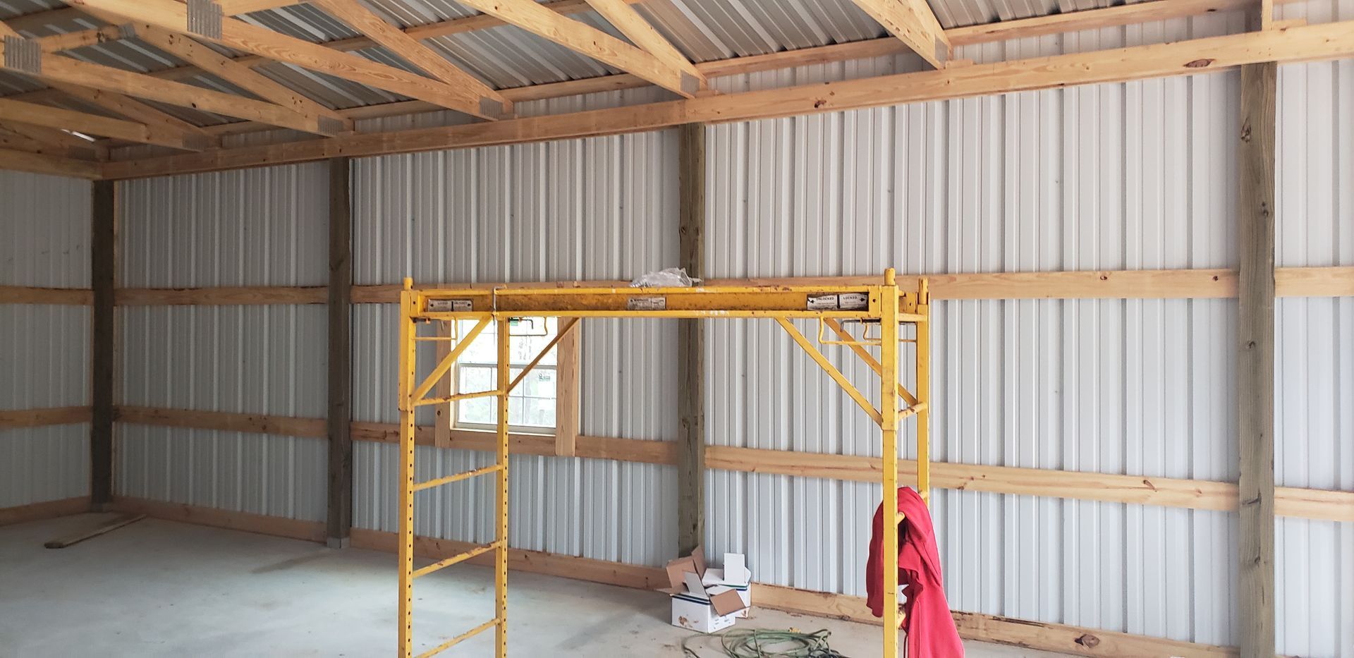 Inside a metal building under construction, yellow scaffolding.